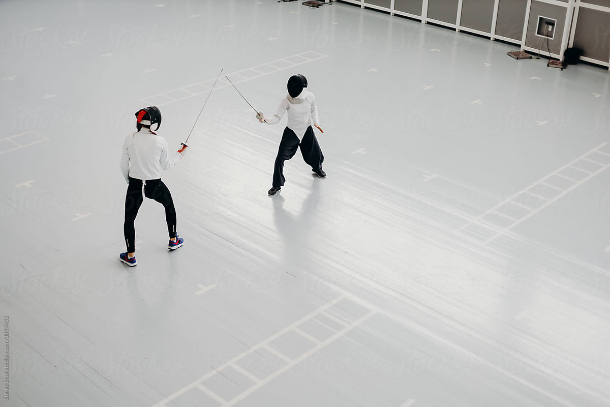 Professional fencers with swords training in gym