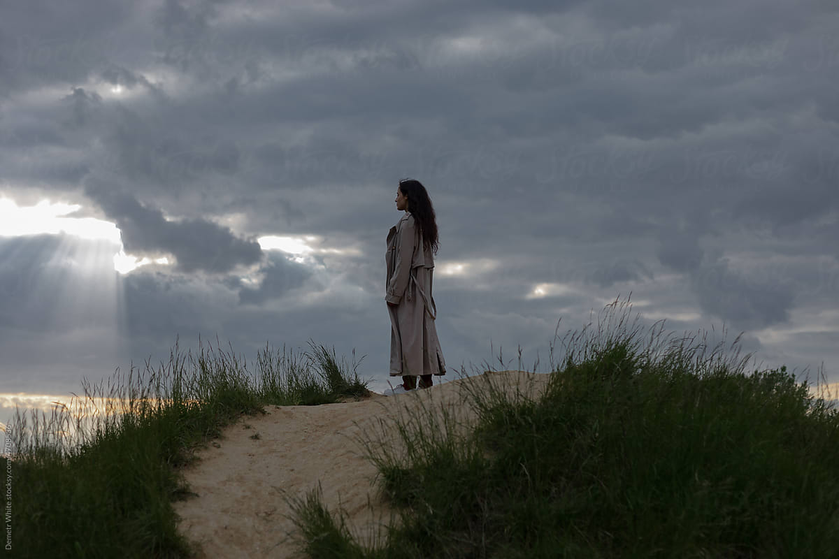 woman in a trench coat against the sky