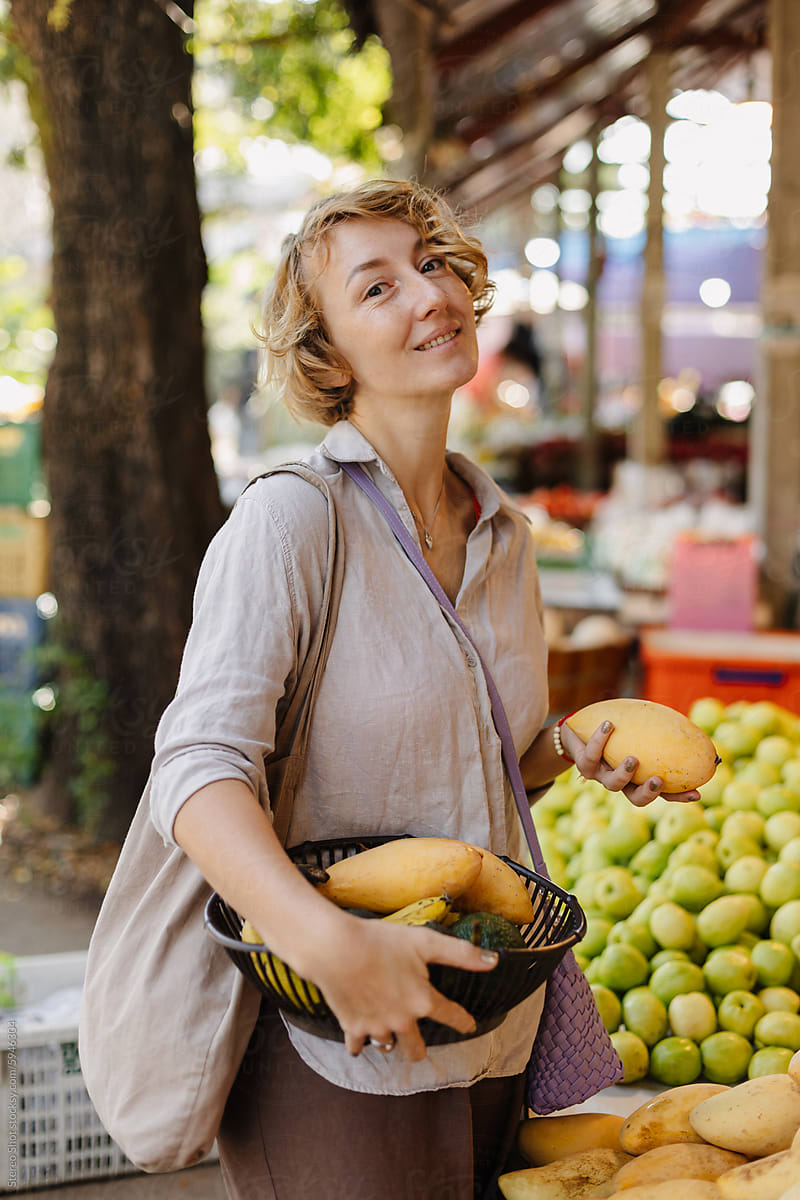 Smiling woman buying mangoes at local market