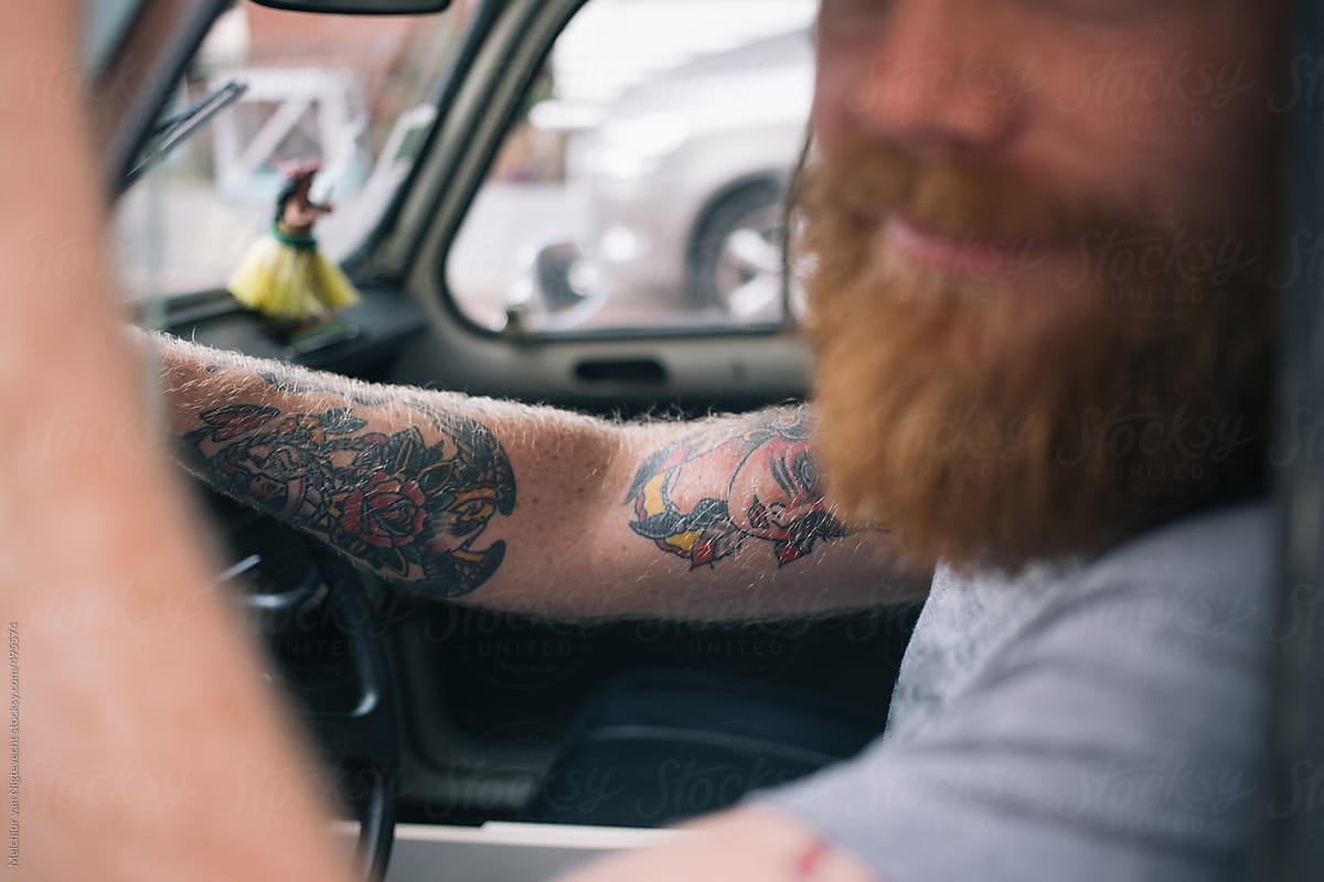 Young man with beard and tattoos is waiting in his car