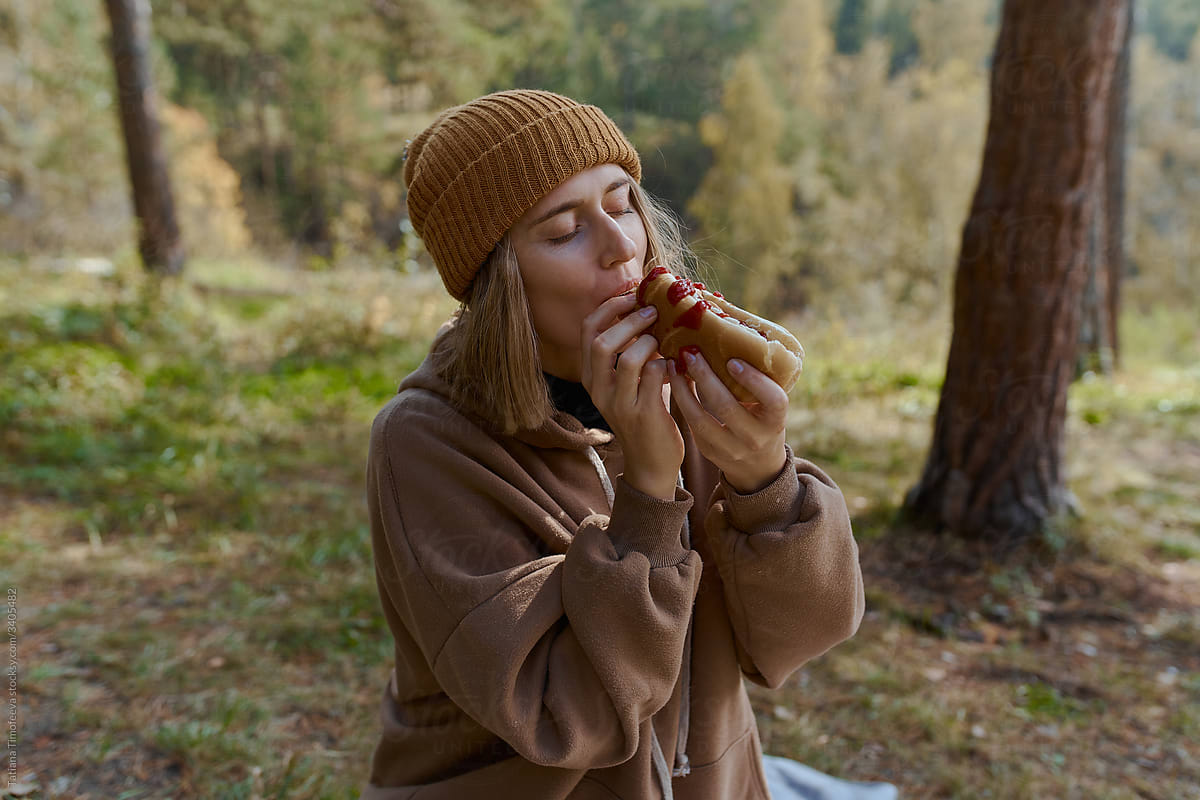 woman outdoors eating hand made lunch hot dog