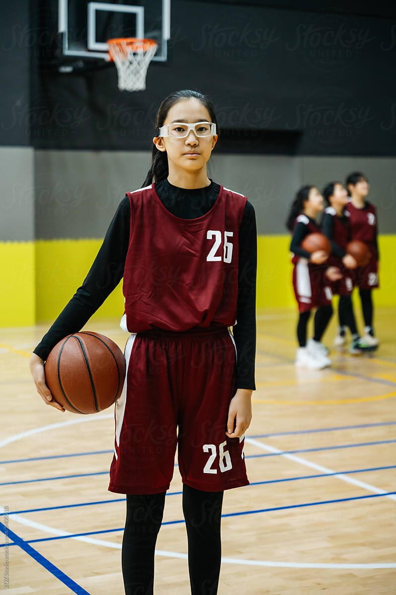 Teenage girl wearing basketball uniforms and looking at camera