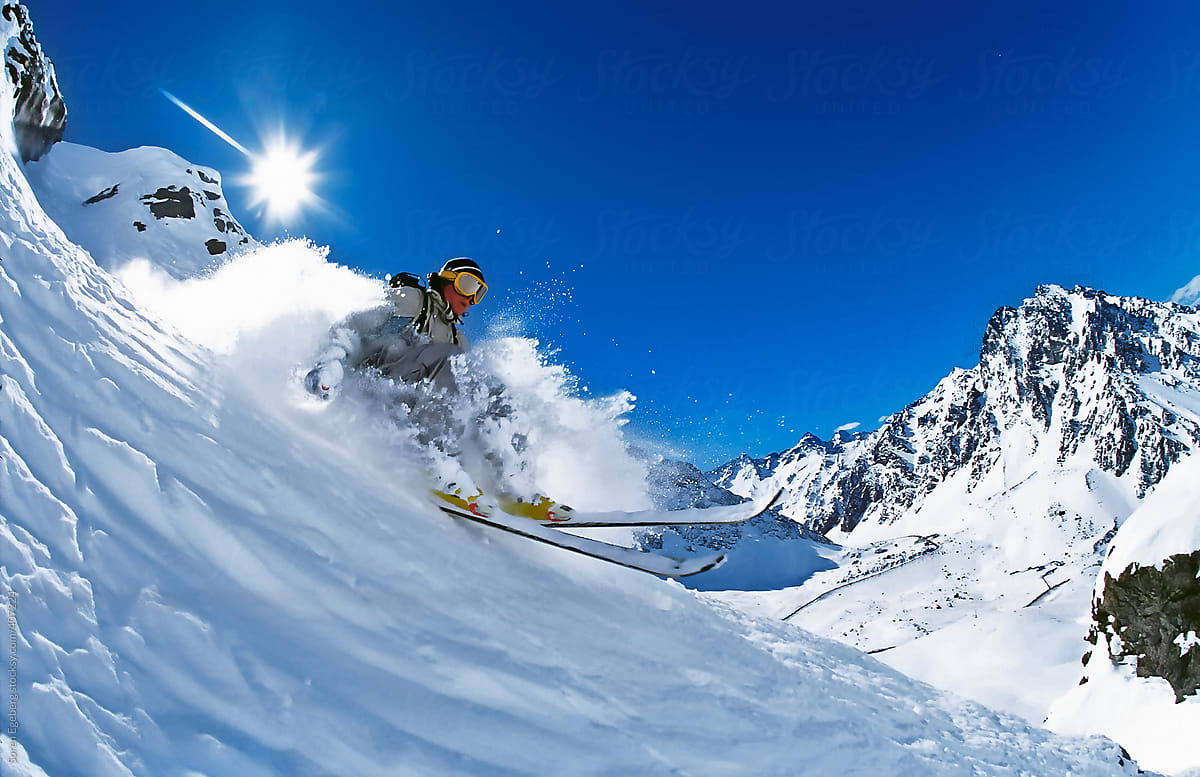 Man Skiing Powder Snow In Winter Mountains With Blue Sky And Sun Burst In Background By Soren Egeberg Ski Action Stocksy United