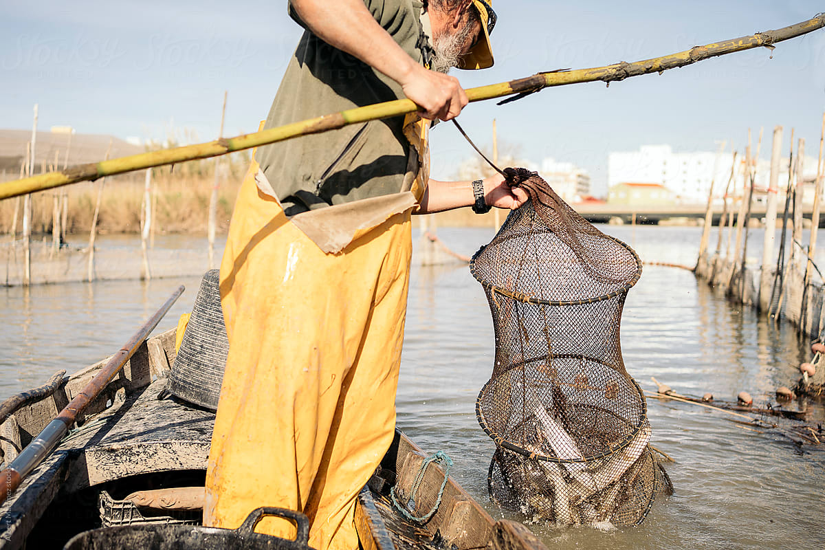 Fisherman holding push pole and catching fish with his net