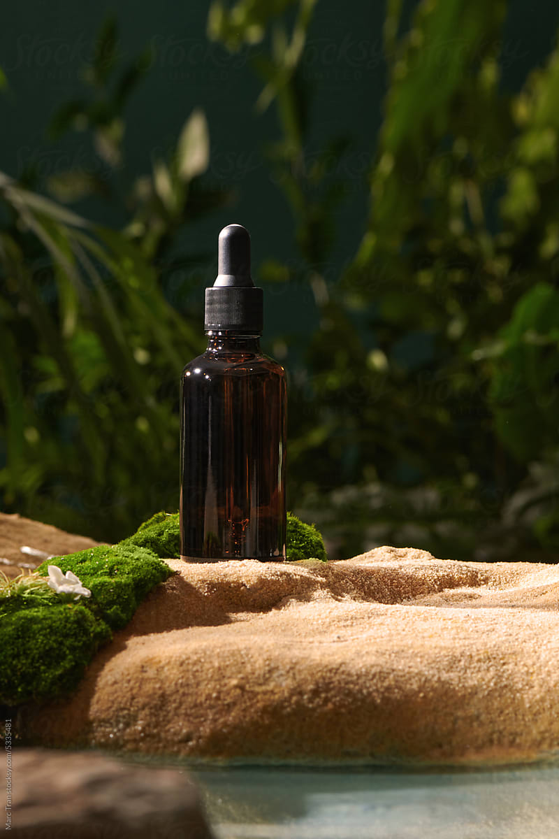 Dark cosmetic bottle of aromatic oil in a warm forest setting