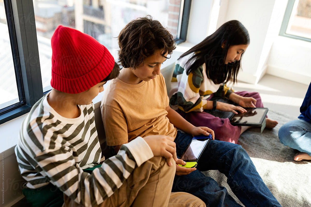 Teen friends playing with electronics in playroom