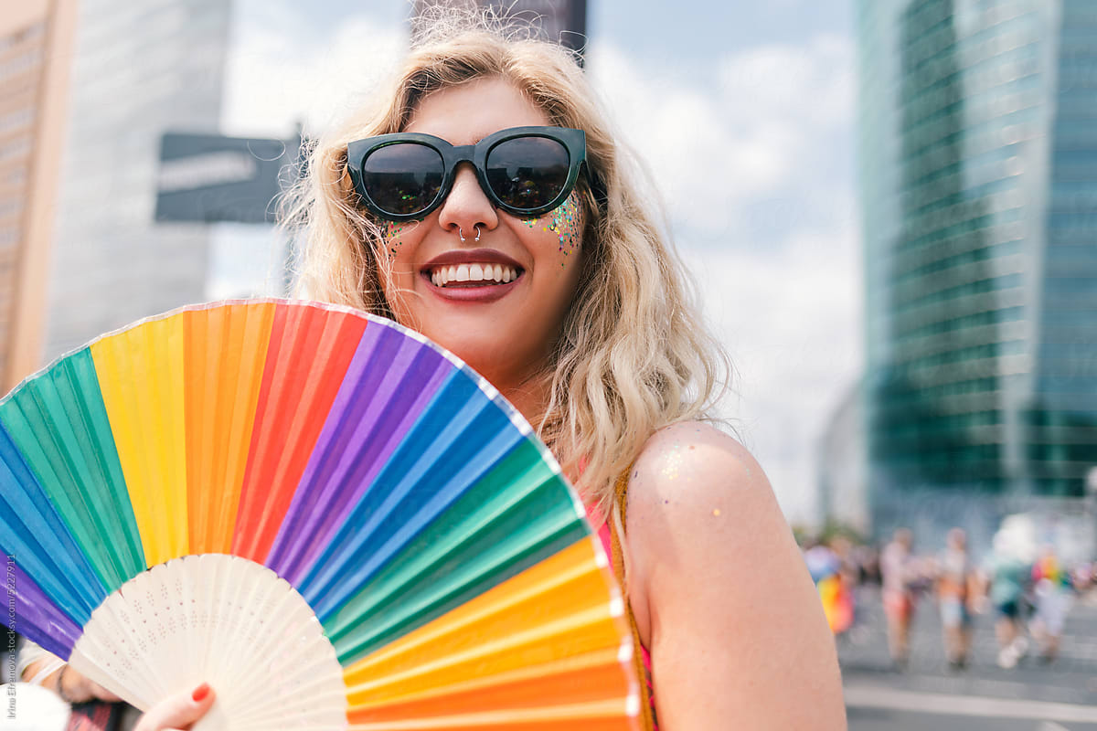 Proud and Glittering blond woman in sunglasses and rainbow hand fan