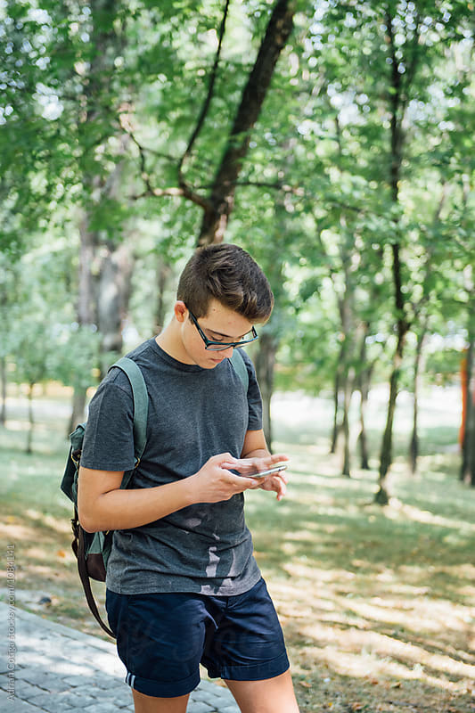 Teenager playing location-based augmented reality game on his smartphone in the city