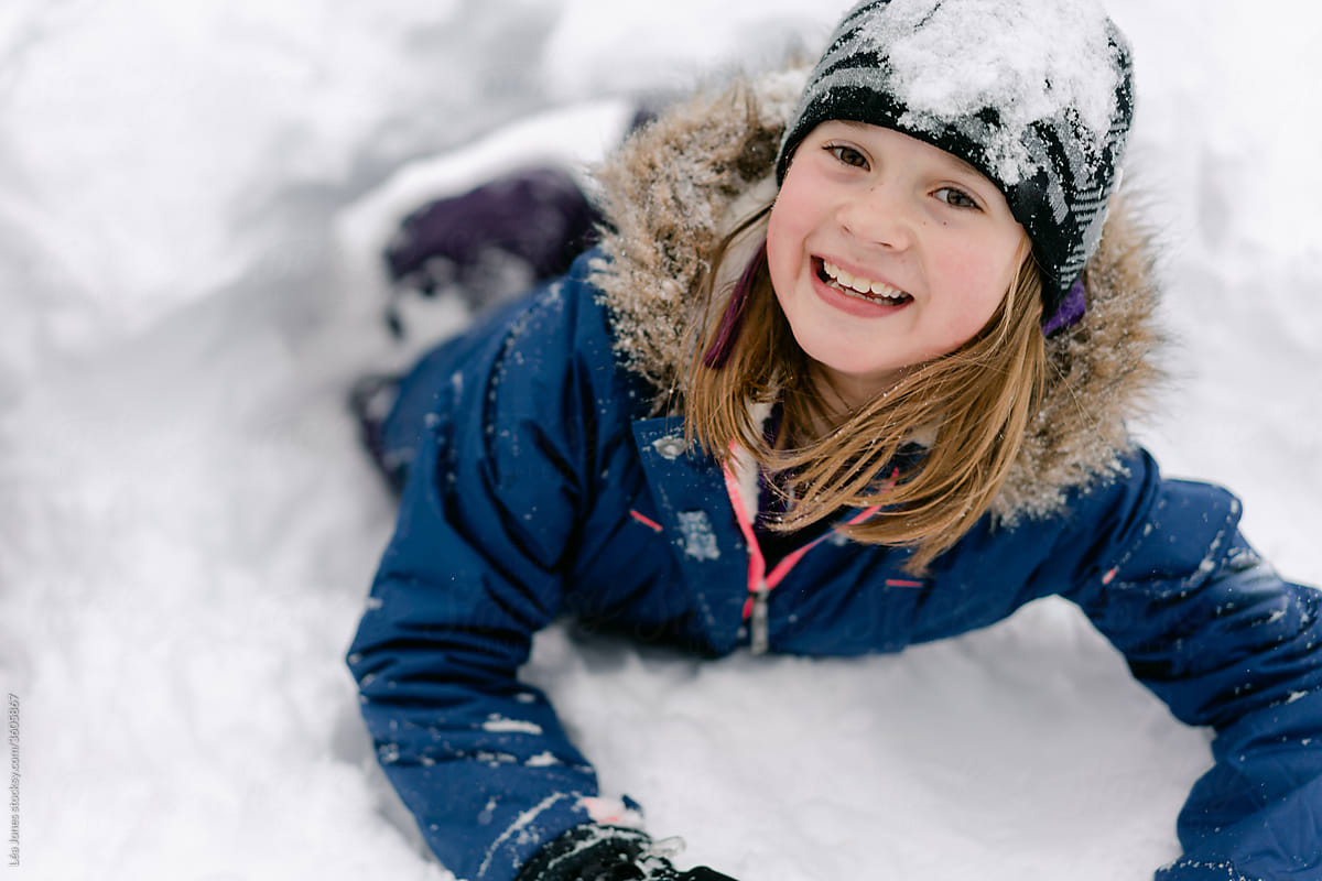 young girl digging a tunnel in the snow