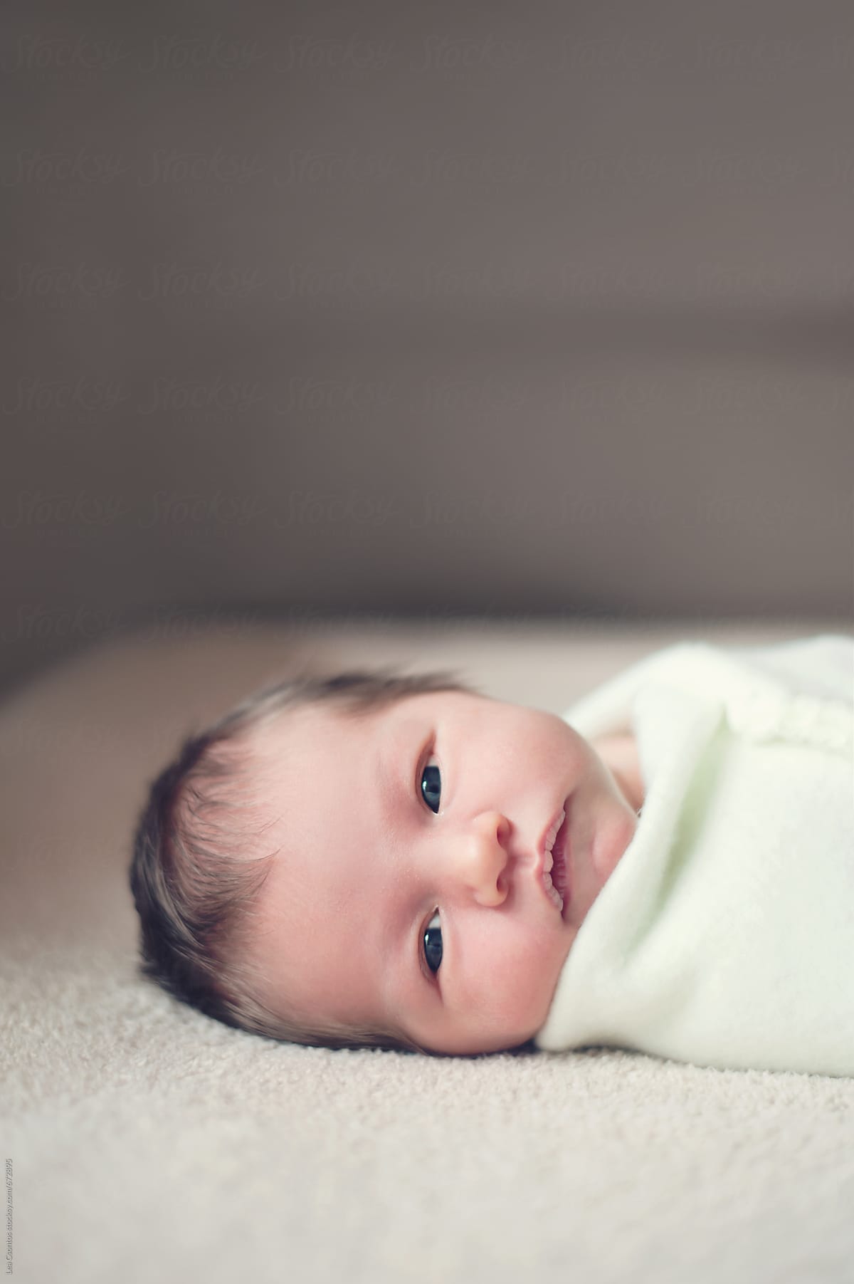 Gorgeous Awake Newborn Baby Wrapped In A Blanket And Looking At Camera