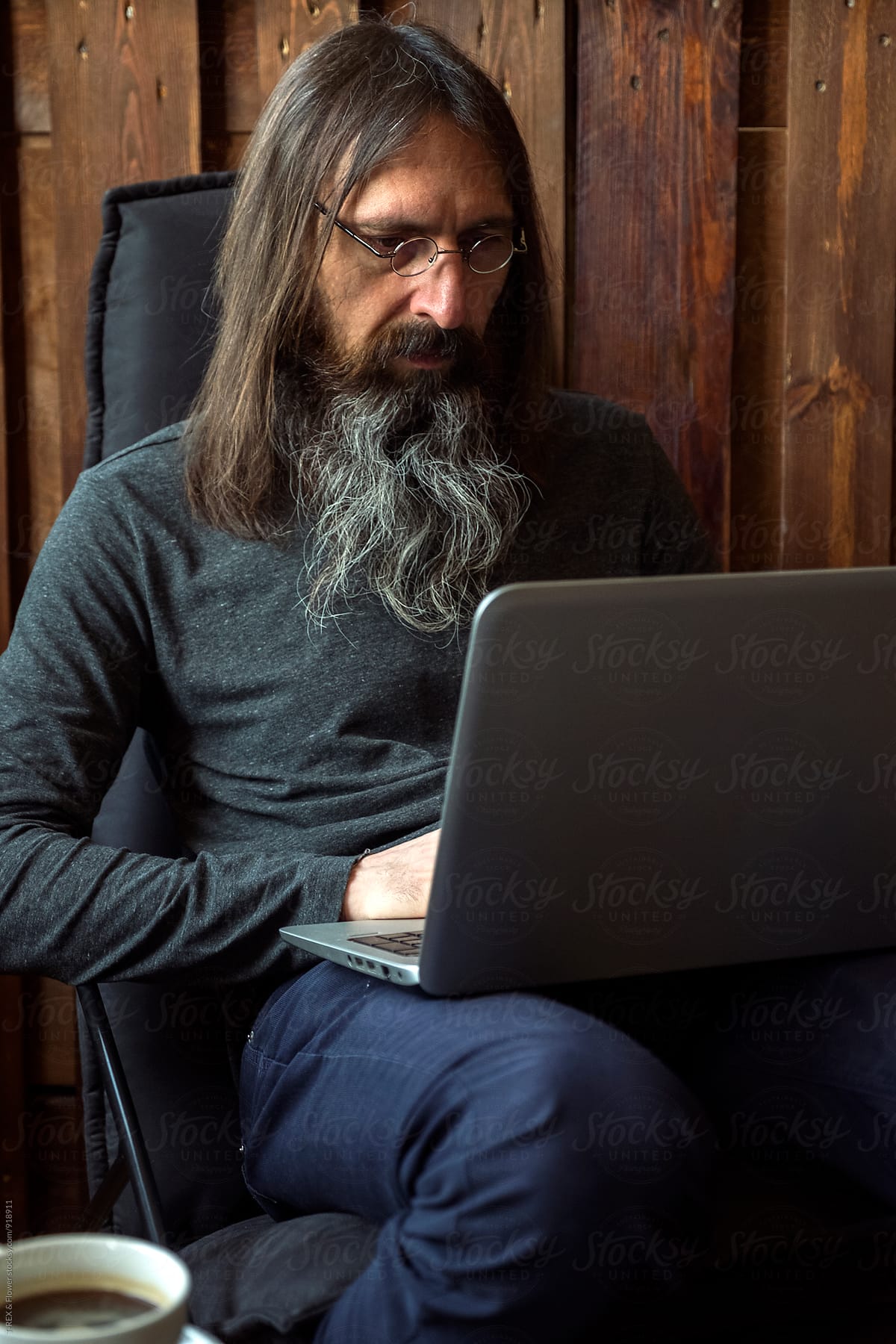 Long haired man sitting on chair while using laptop