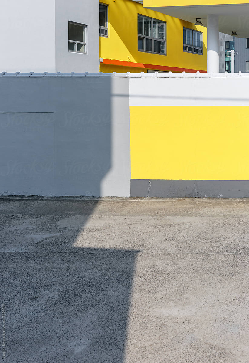 The shadow of the building was cast on the yellow-painted fence.