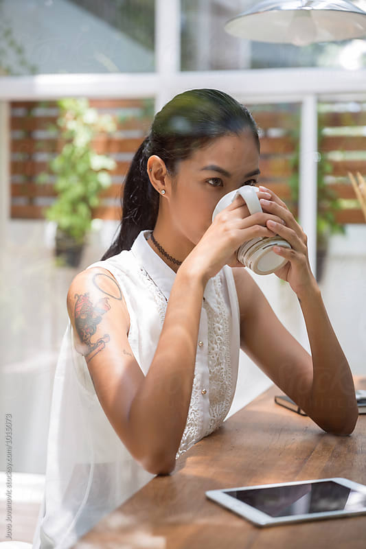 Beautiful young Asian woman drinking coffee