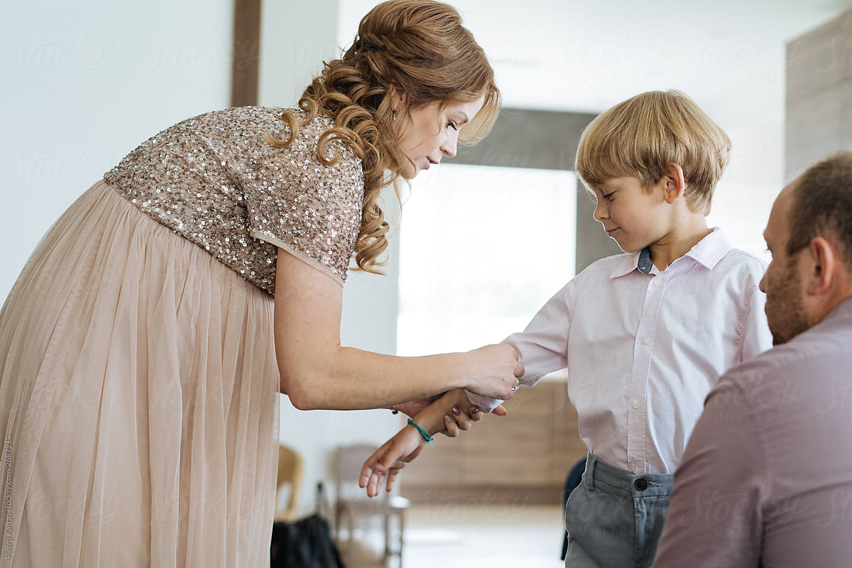 Mother helping son with shirt before party