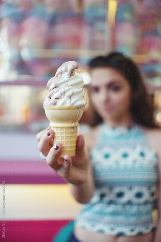 A teenage girl eating ice cream at a carnival