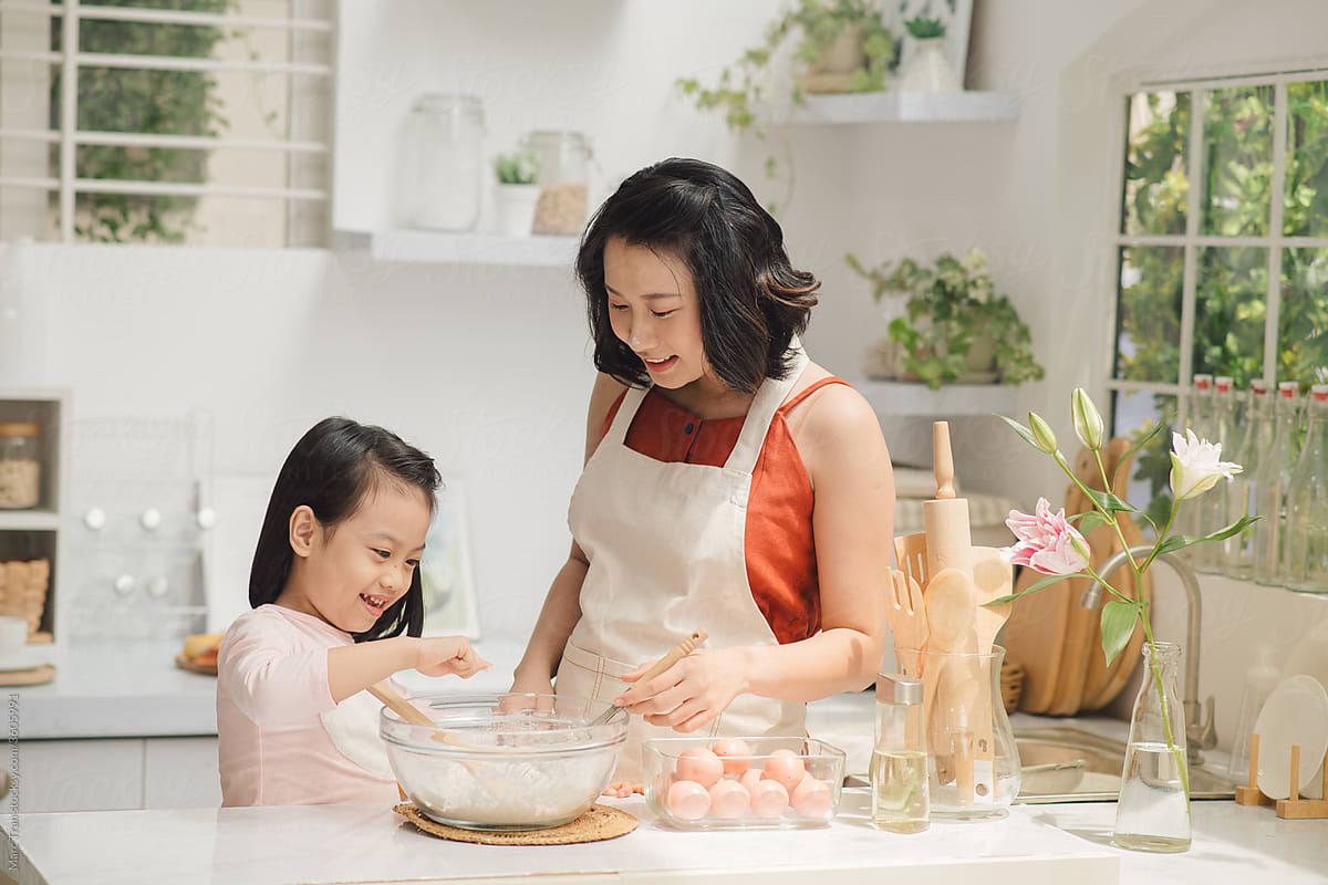 A young mother and her daughter making the cake at home