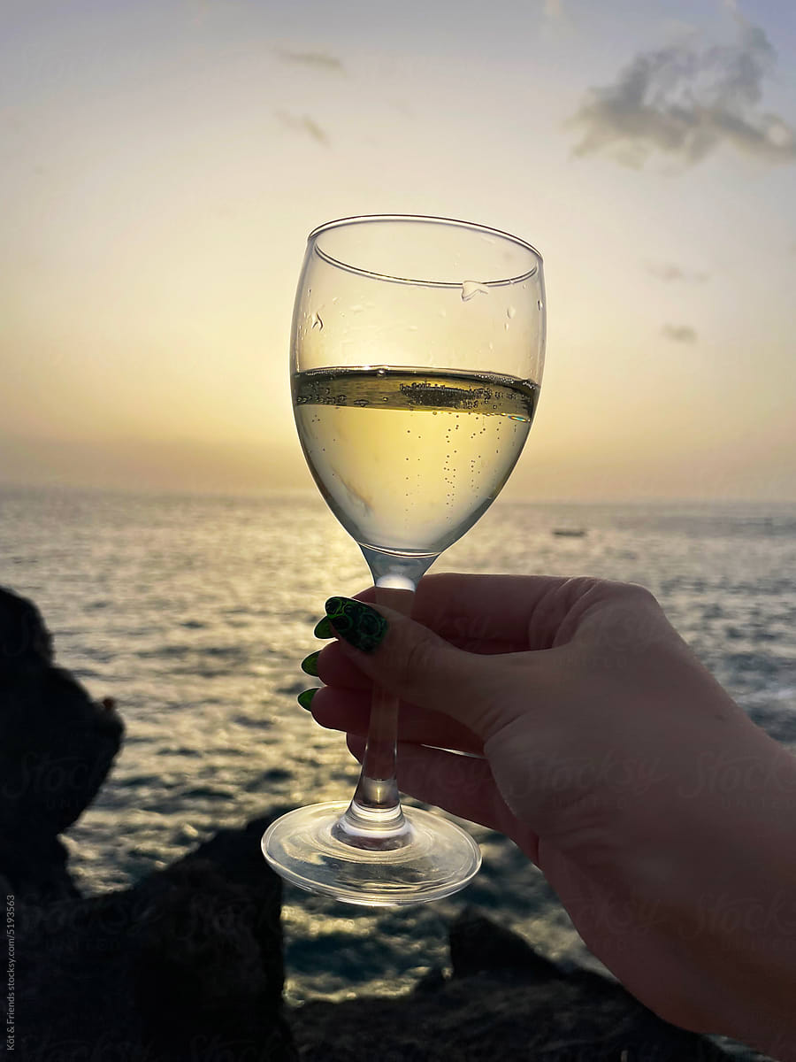 Hand Holding Glass Of Beverage At Sunset