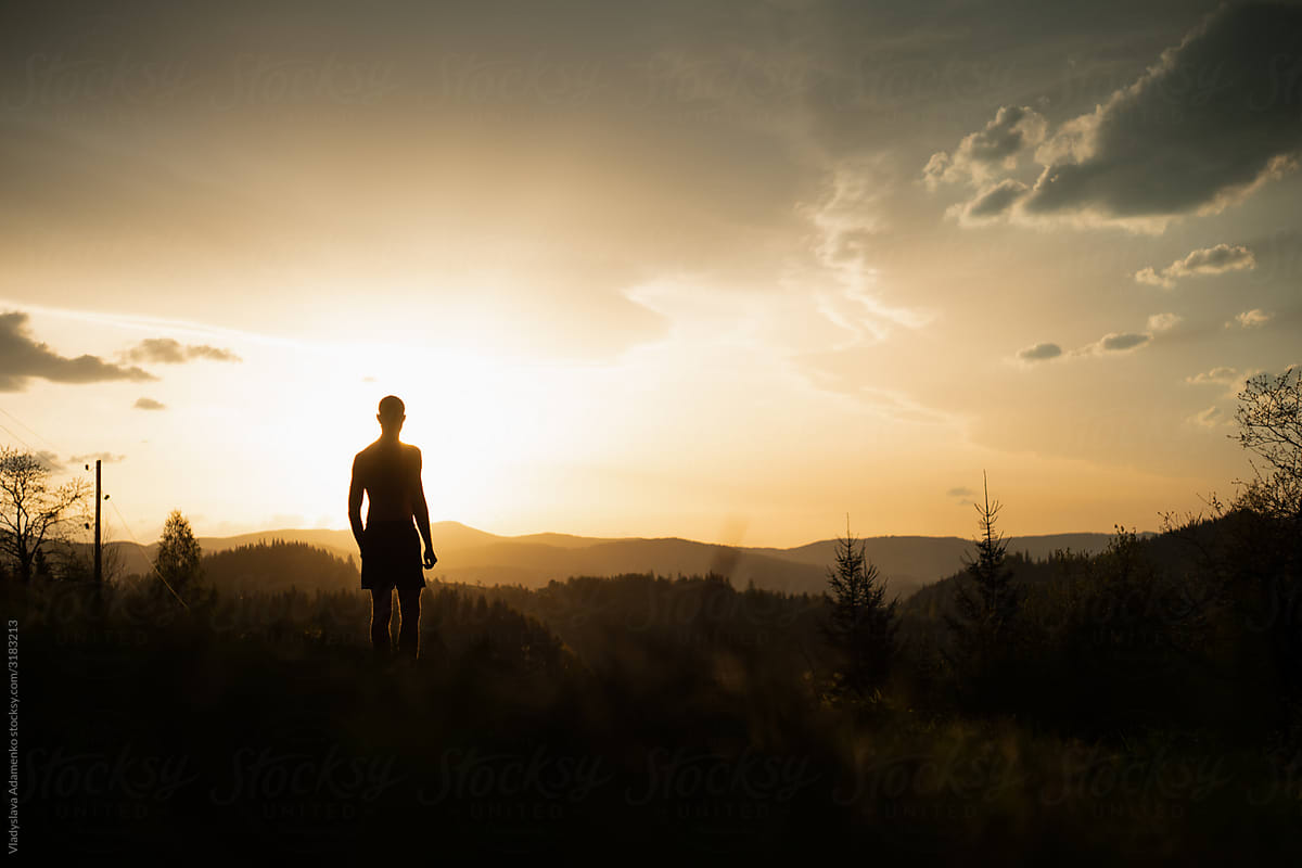 Man looking at the dramatic sunset in the mountains