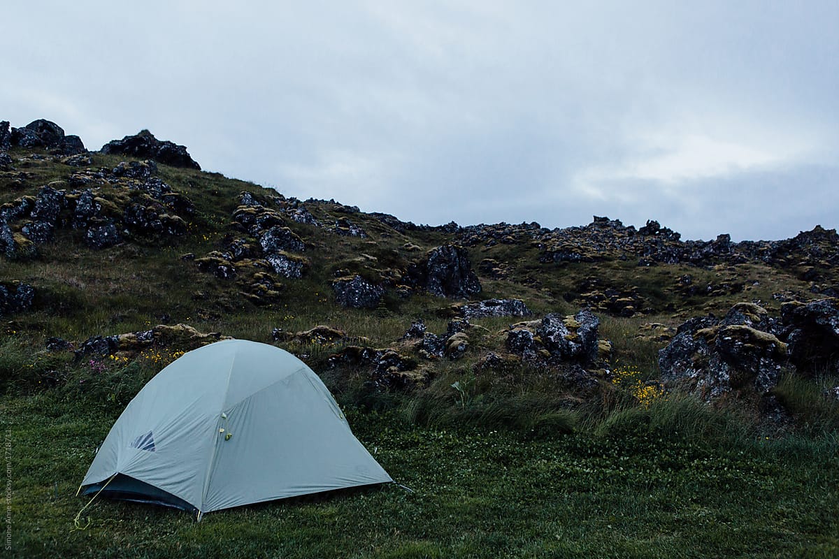Camping tent set up in the rocks and volcanic land and greenery of Iceland