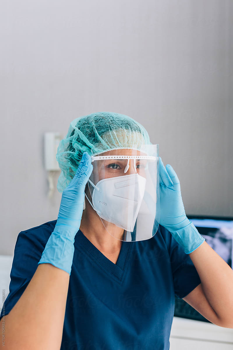 Dental surgeon woman wearing mask and cap while looking away wit