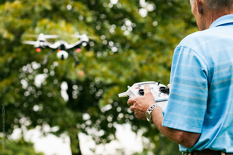 Drone Hovering As Senior Man Uses Remote Control