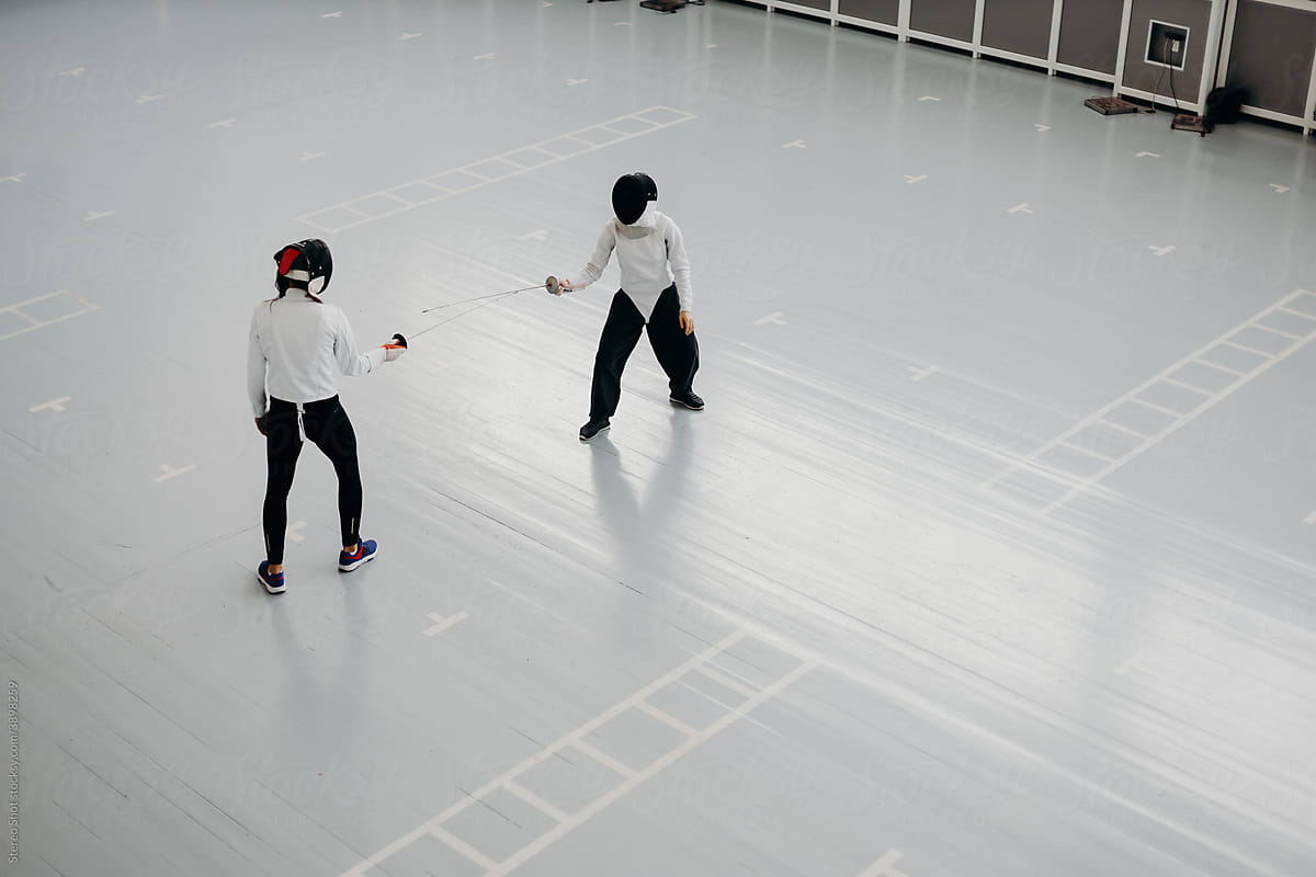Professional fencers practicing with swords in gym
