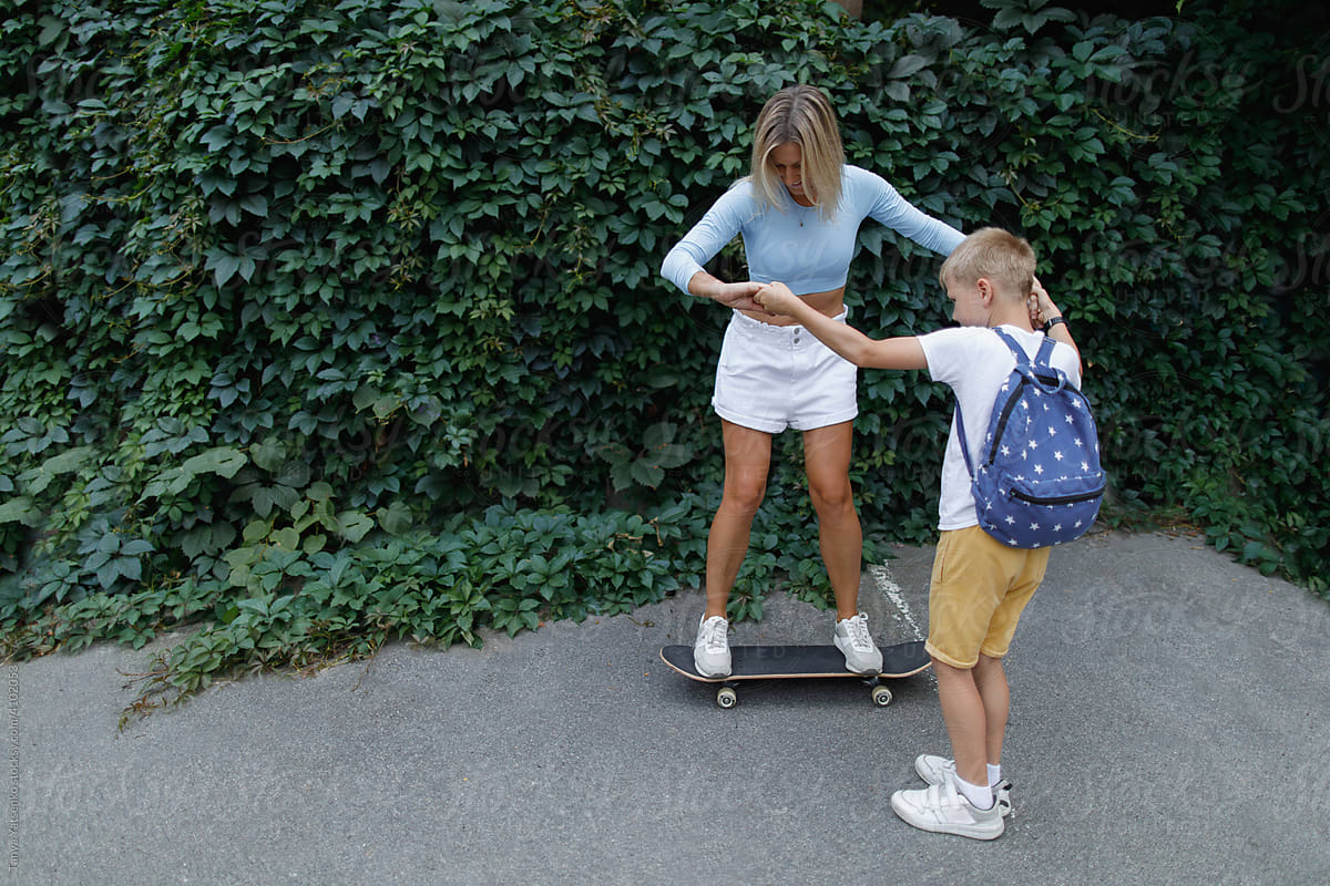 A woman on a skateboard with her son\'s help