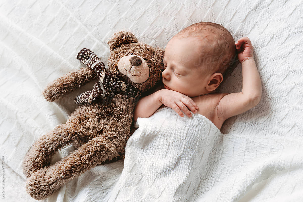 Newborn baby sleeping with his toy bear