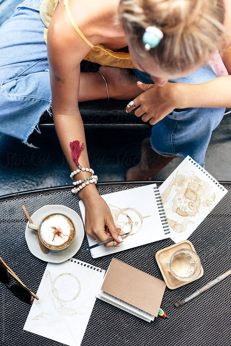 Blonde woman drawing coffee art in cafe