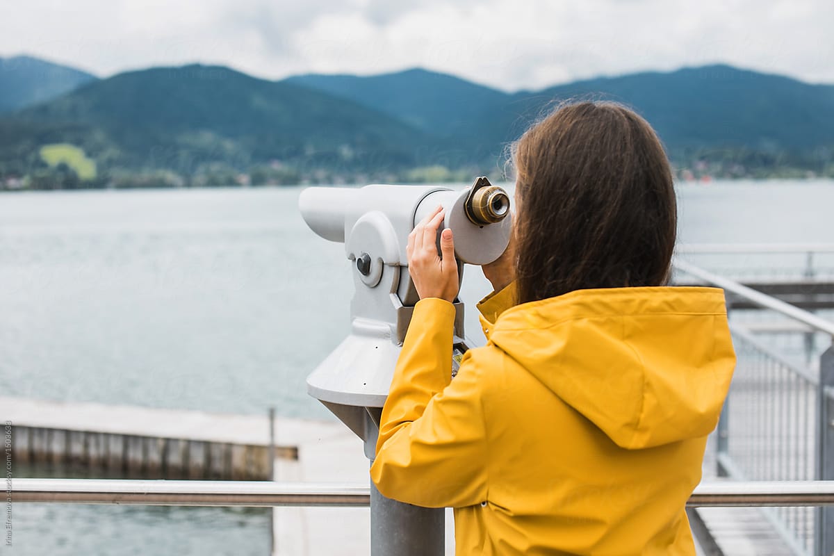 Girl in a yellow raincoat looking through telescope