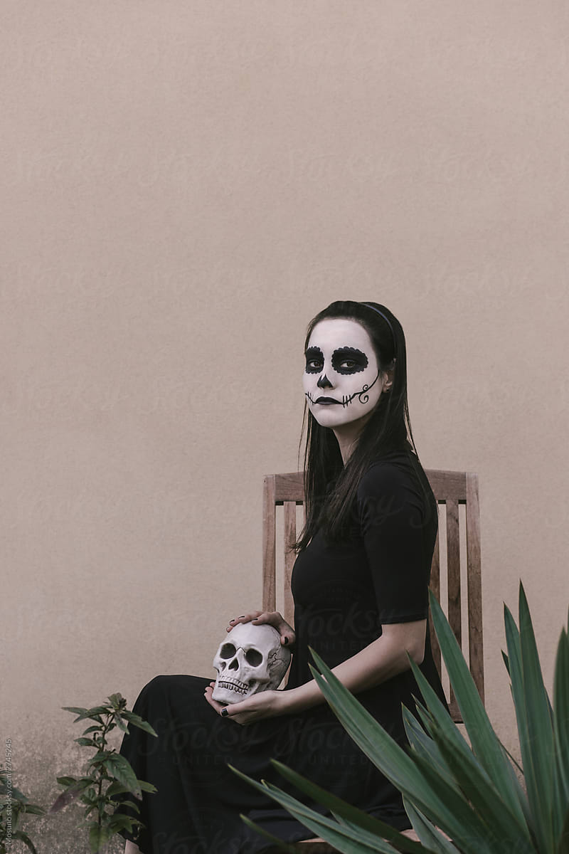 Elegant woman in Halloween black dress with skull makeup