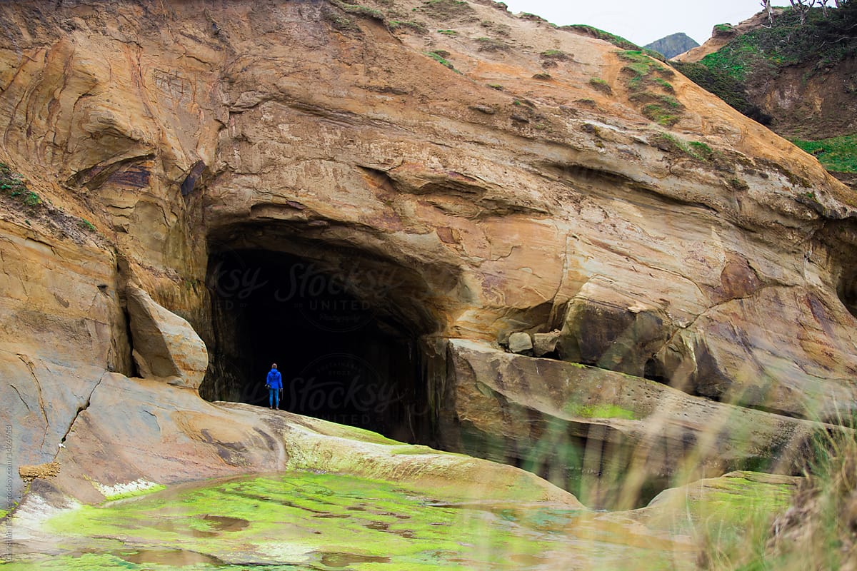A tiny figure standing in the opening of a huge sea cave on the West Coast of the USA