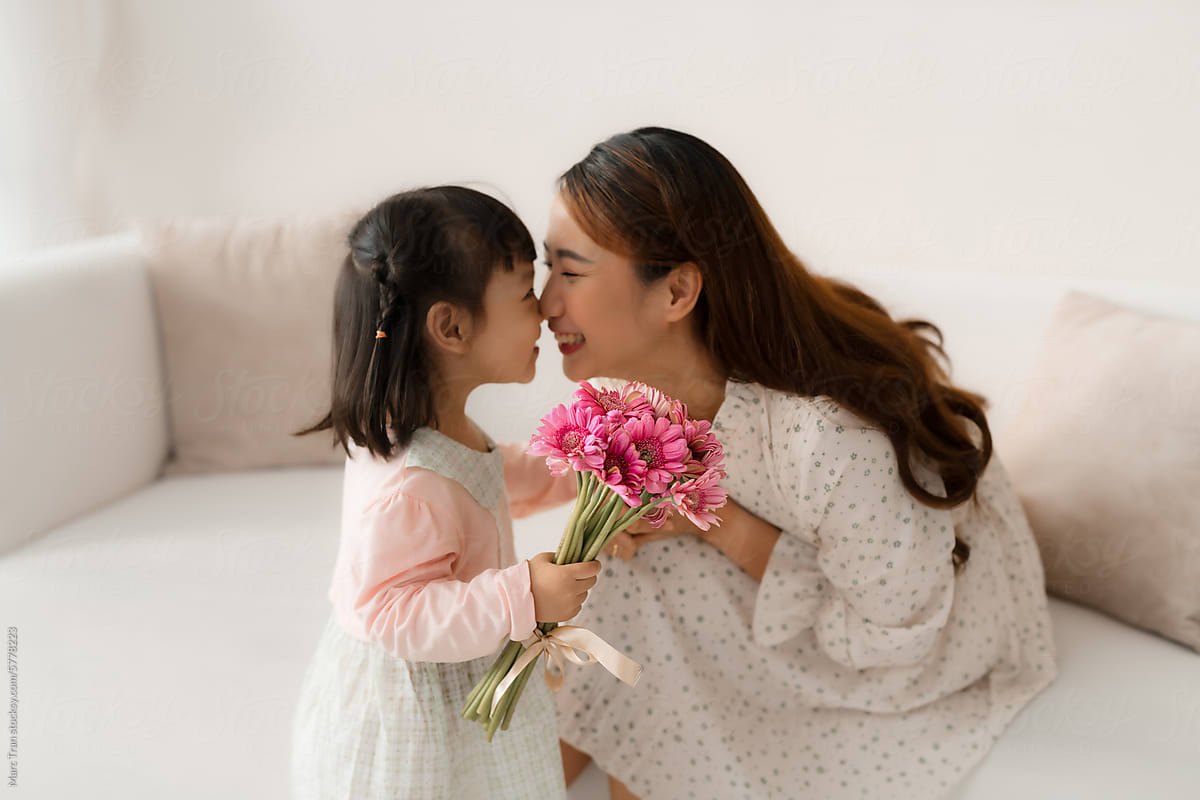 Cheerful mother and a little daughter embrace. Focus on flowers