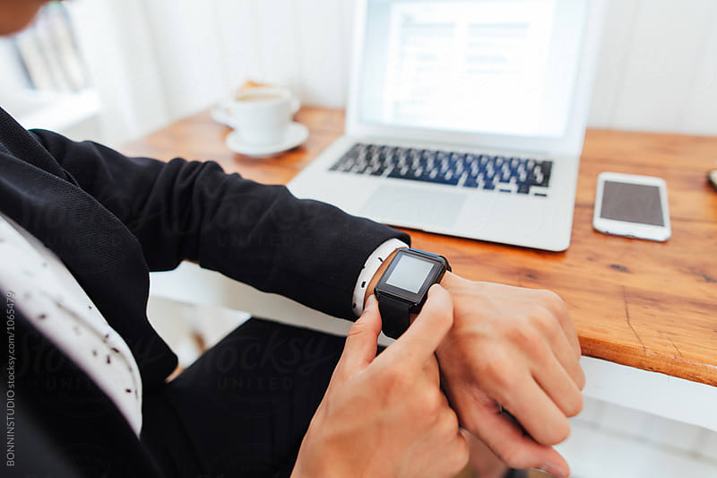 Closeup of a businessman using his smart watch working in a coffee bar.