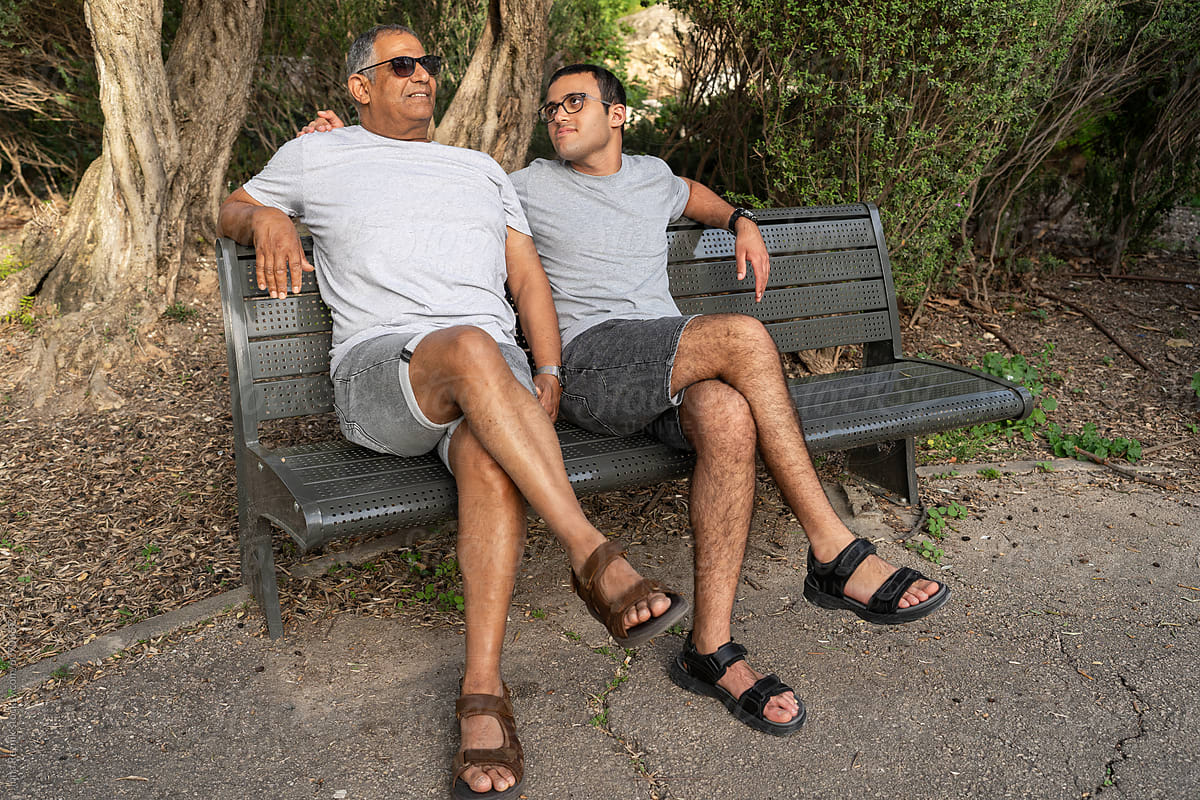 Father and Son on Park Bench. Relaxed Afternoon In The Shade.