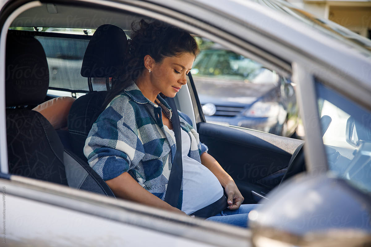 Pregnant woman adjusting seat belt around belly