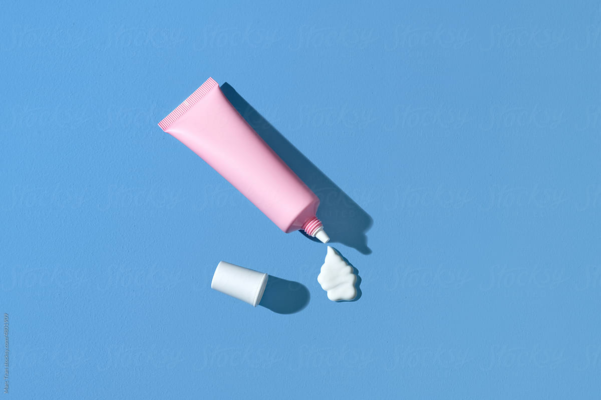 Face cream tube and stroke on blue background