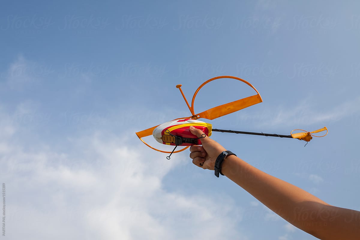 Girl holding a toy helicopter for flying in the blue sky