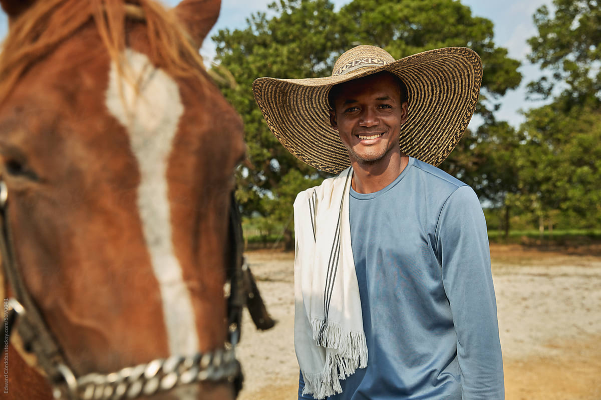 Young smiling farmer portrayed with his horse on a Colombian ranch.