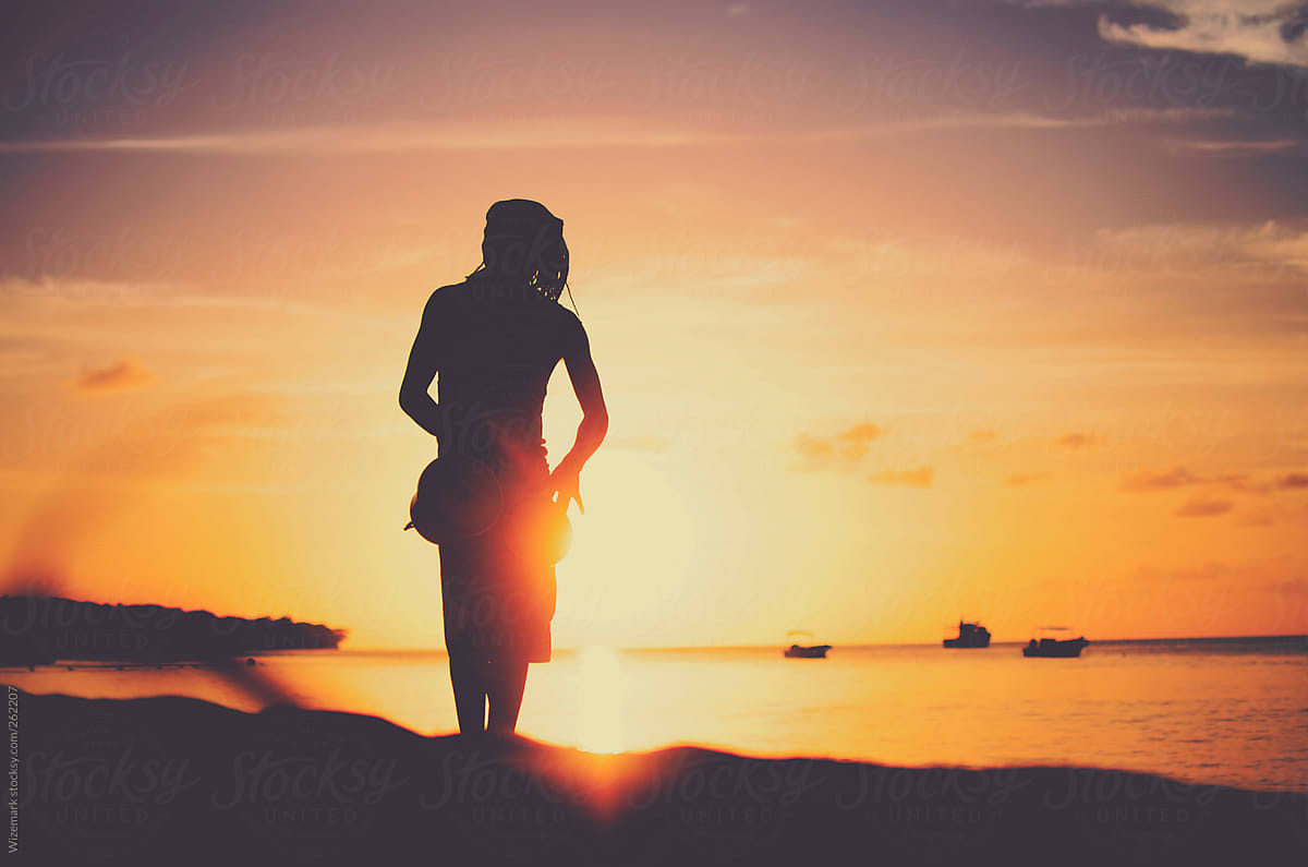 Silhouette of a young rasta man playing drums on the beach during beautiful  summertime sunset by Wizemark - Stocksy United