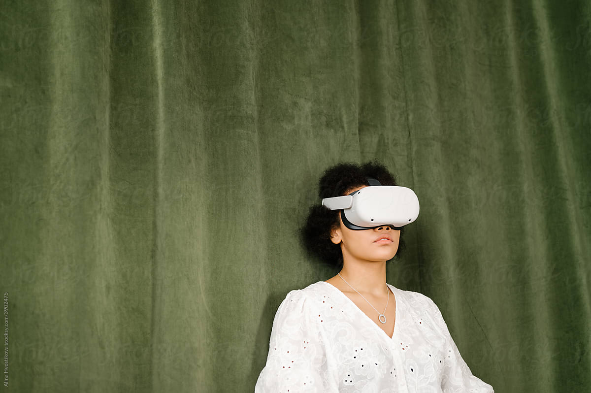 Black woman in VR headset leaning on green wall