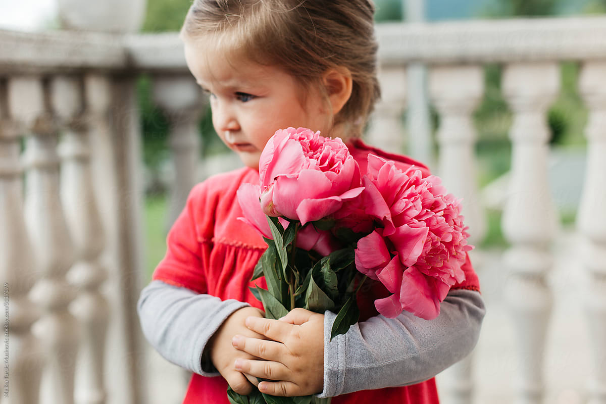 Little girl holding bouquet of peonies
