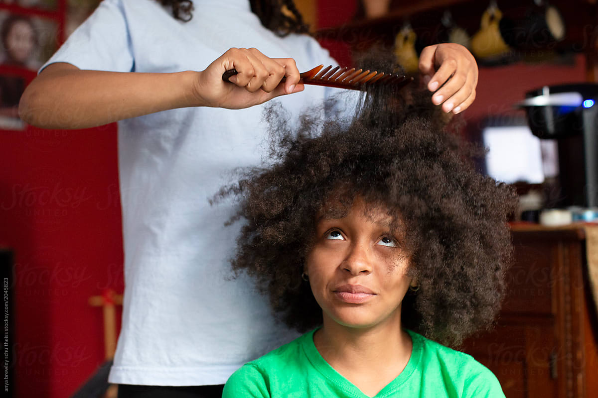 Girl helping to comb her sisters kinky hair