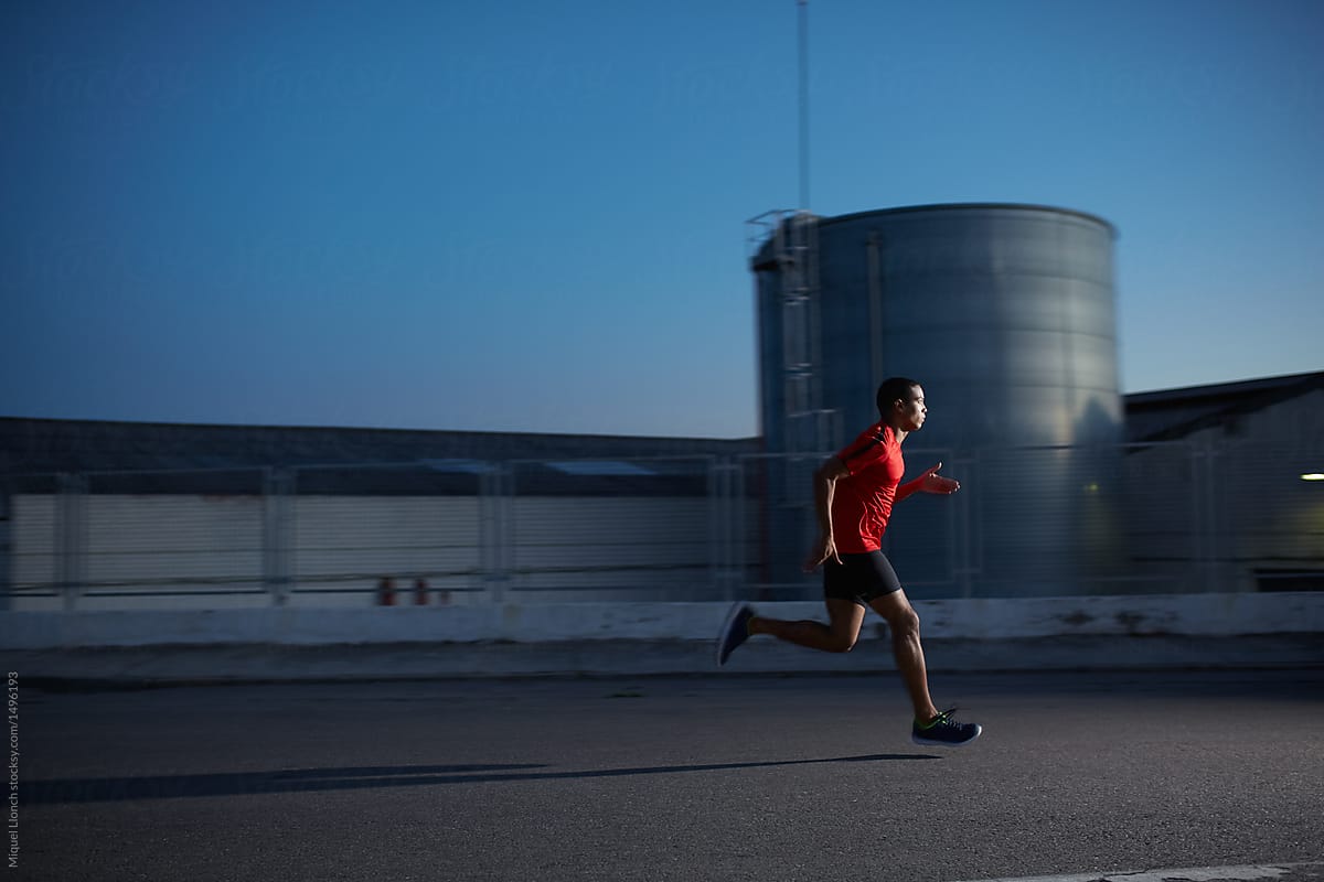 Young runner in red at night in industrial area