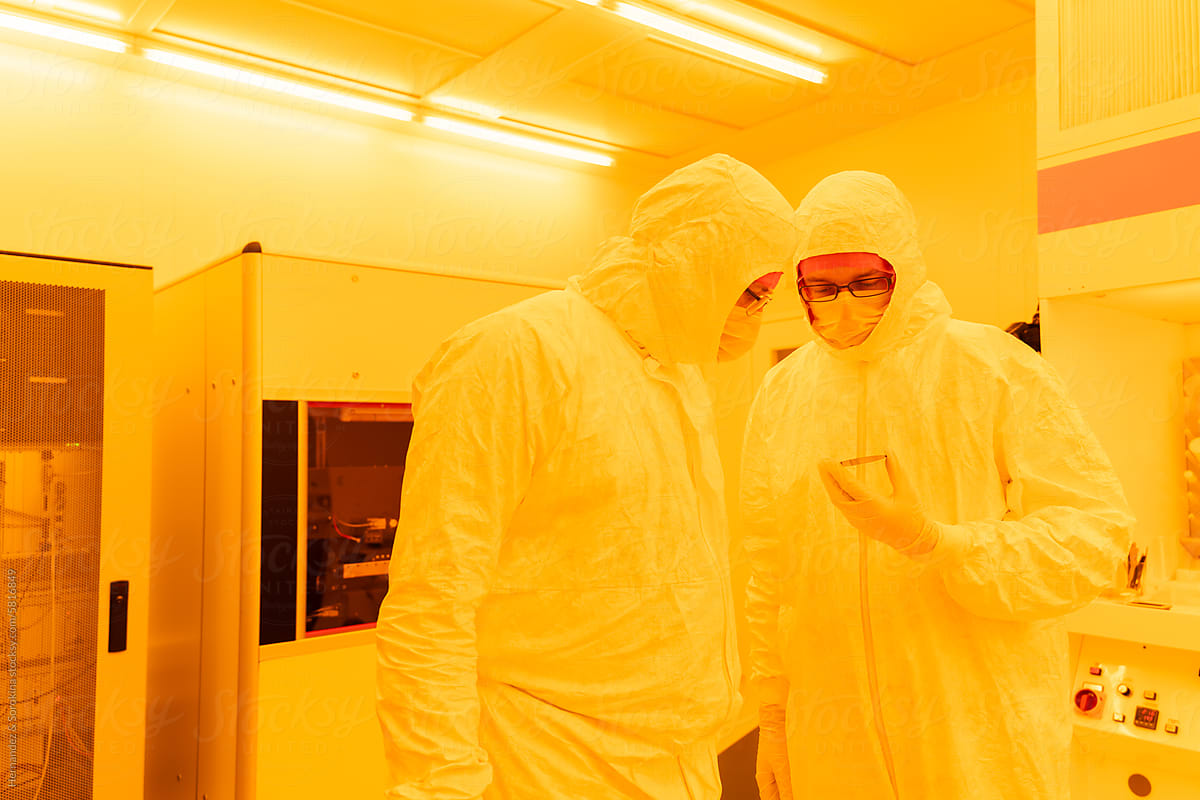 Scientists Analysing Silicon Sample Together In Clean Room