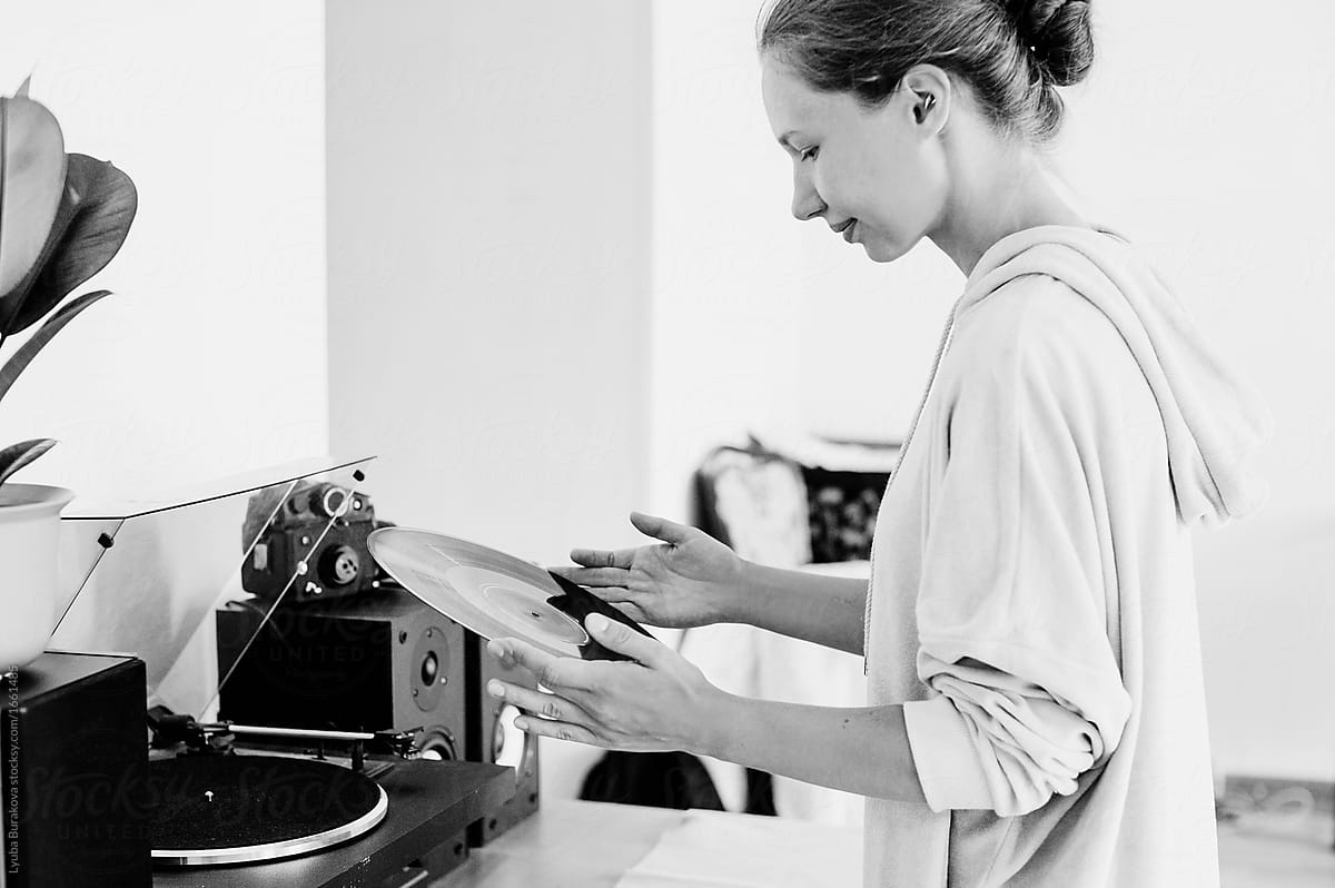 Girl putting on a vinyl record on the spinning plate at home