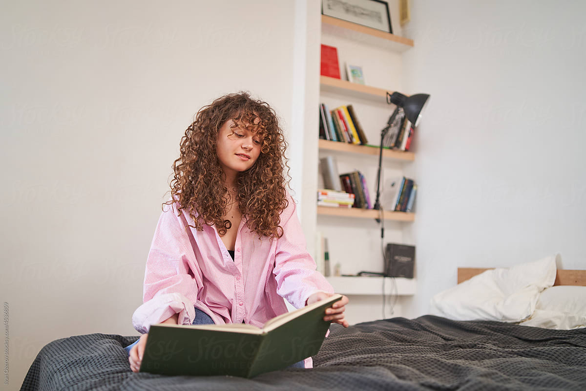 Charming woman reading book in bedroom