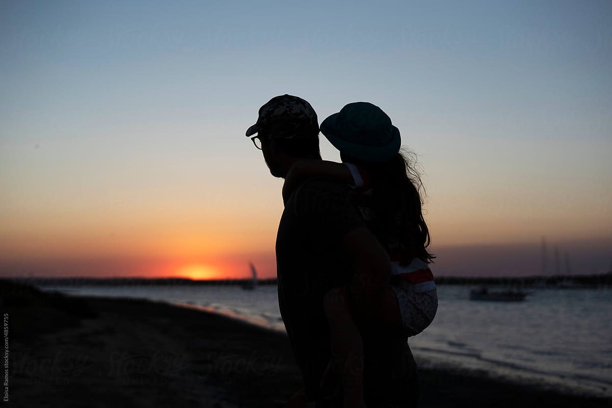 Father with his daughter enjoying the sunset at the beach
