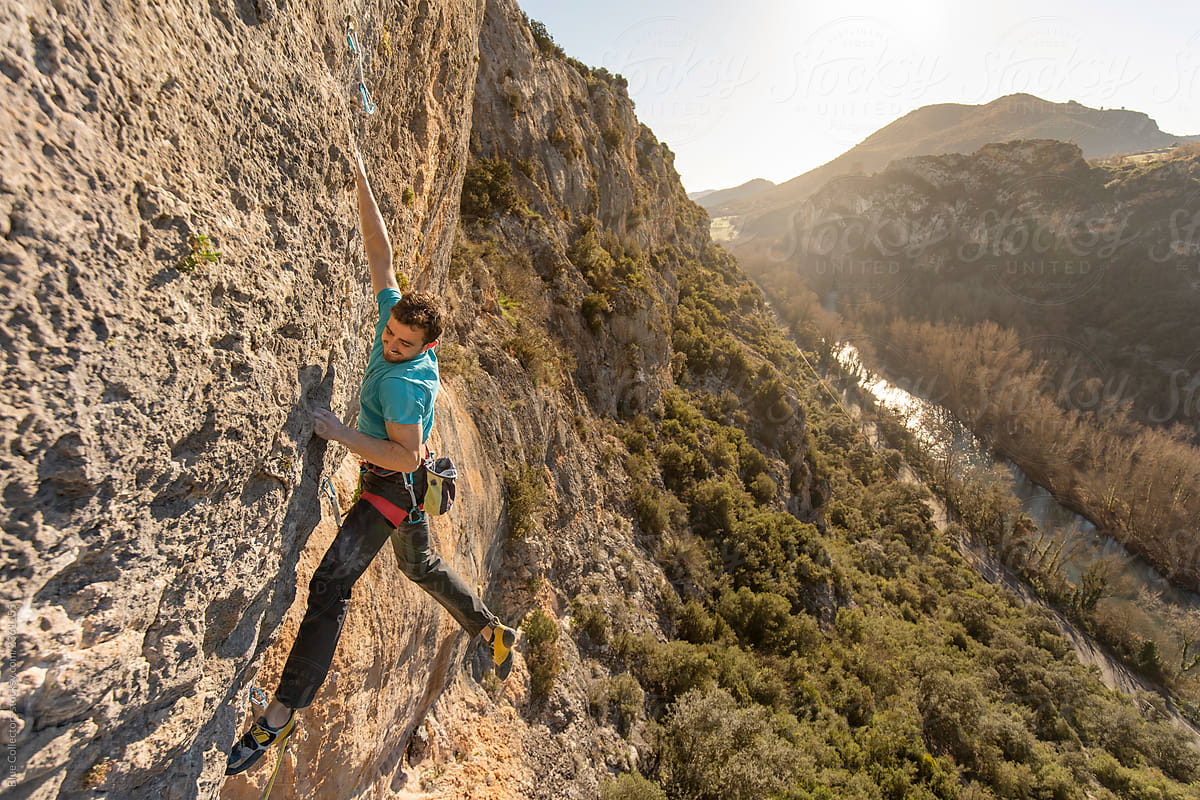 Rock climber climbing a mountain cliff at sunrise
