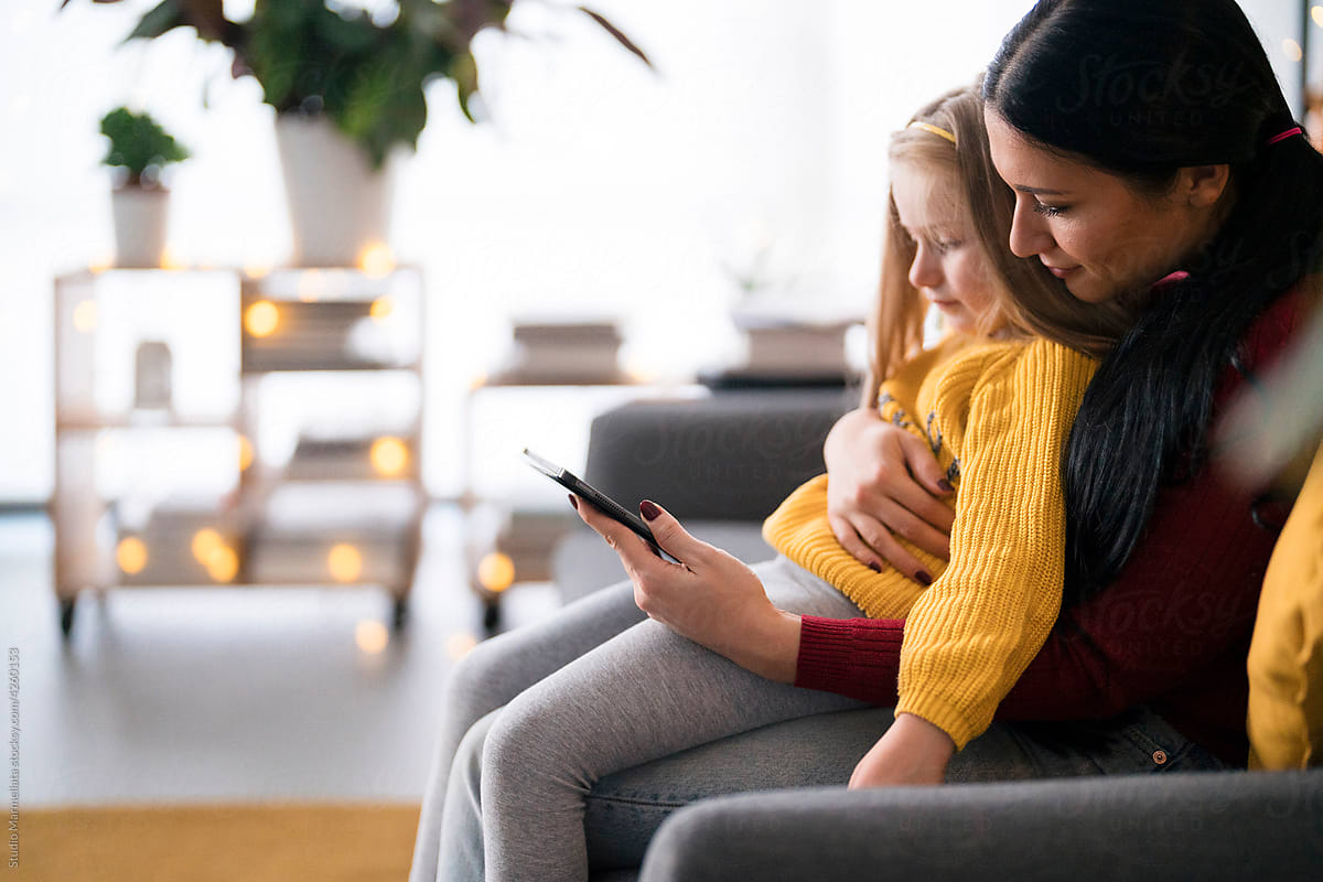 Diverse nanny and girl using tablet